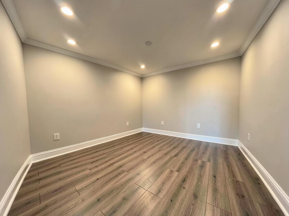Finished interior room with new flooring, crown molding and recessed lighting